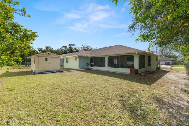 rear view of house featuring a sunroom, a storage shed, and a lawn