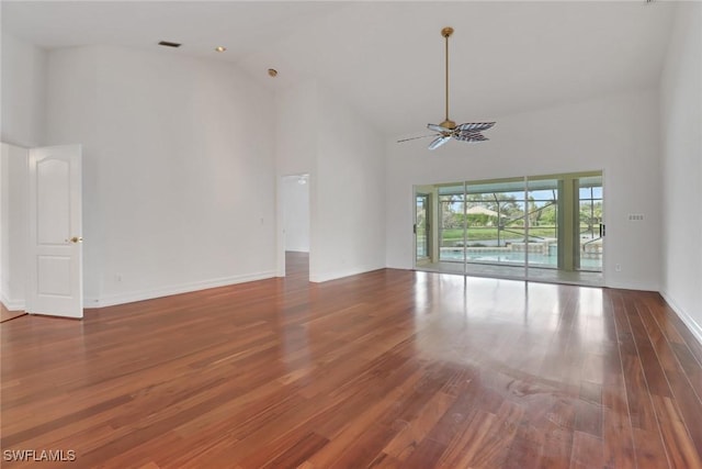 unfurnished living room with ceiling fan, wood-type flooring, and a high ceiling