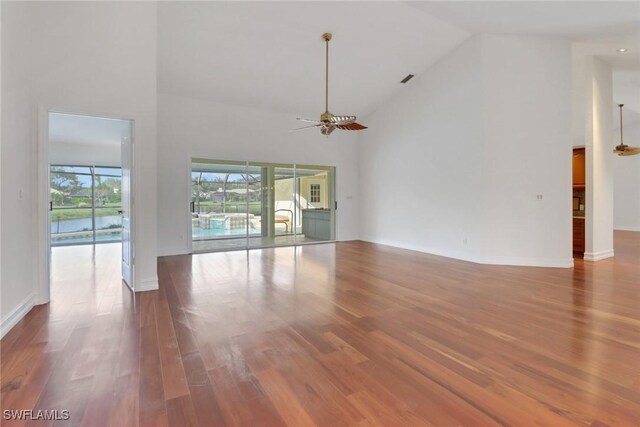 unfurnished living room with hardwood / wood-style floors, ceiling fan, and high vaulted ceiling