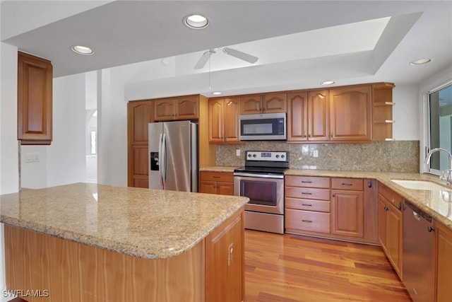 kitchen featuring sink, stainless steel appliances, kitchen peninsula, light hardwood / wood-style floors, and decorative backsplash