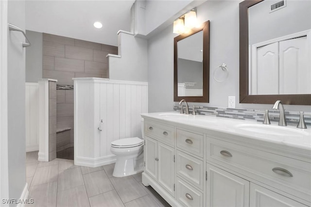 bathroom with tiled shower, vanity, and toilet