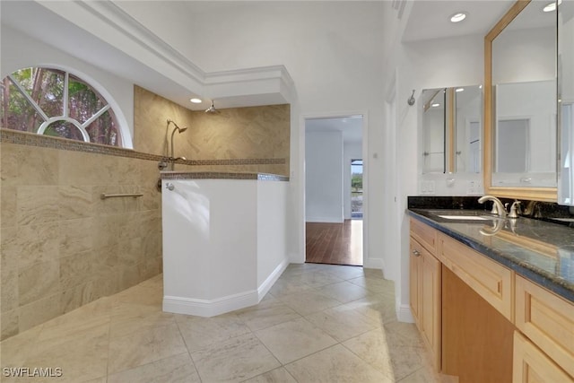 bathroom with tile patterned flooring, vanity, and tiled shower