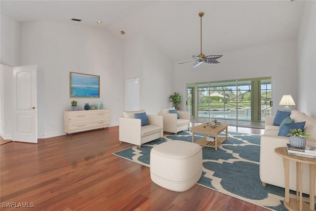 living room featuring ceiling fan, a towering ceiling, and wood-type flooring