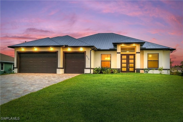 prairie-style home featuring french doors, a garage, and a lawn