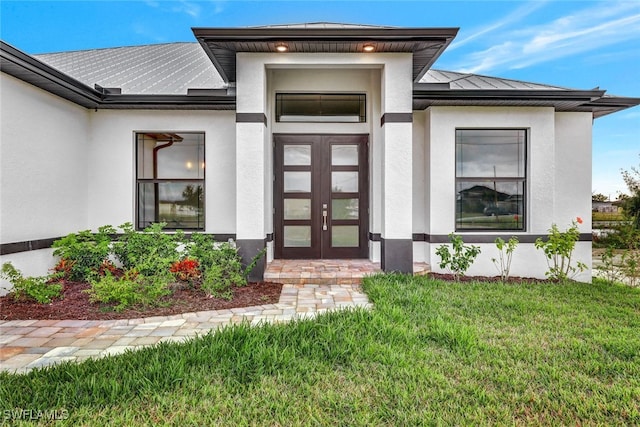 property entrance with french doors and a lawn