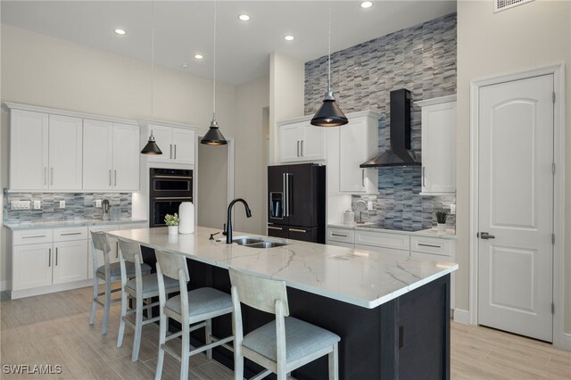 kitchen featuring black appliances, white cabinetry, wall chimney range hood, and sink