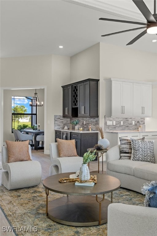 living room with light hardwood / wood-style floors and ceiling fan with notable chandelier