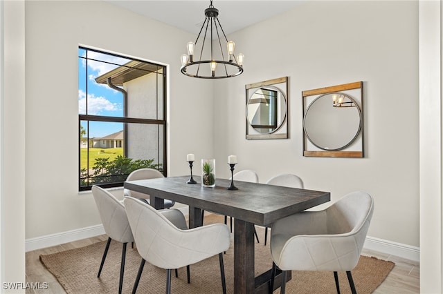 dining space with light wood-type flooring and an inviting chandelier