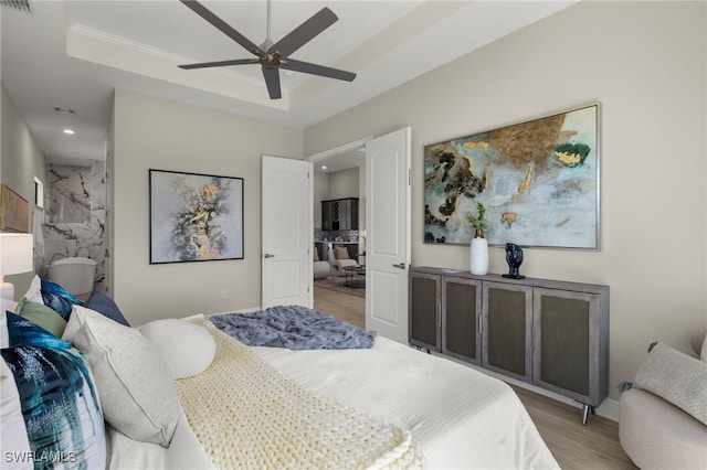 bedroom featuring light hardwood / wood-style floors, a raised ceiling, ceiling fan, and ornamental molding