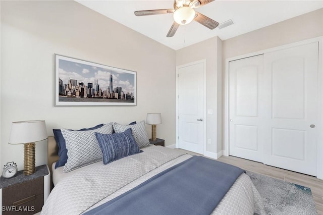 bedroom with a closet, light hardwood / wood-style flooring, and ceiling fan