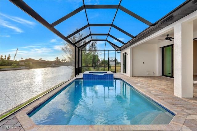 view of pool with glass enclosure, a water view, ceiling fan, an in ground hot tub, and a patio area