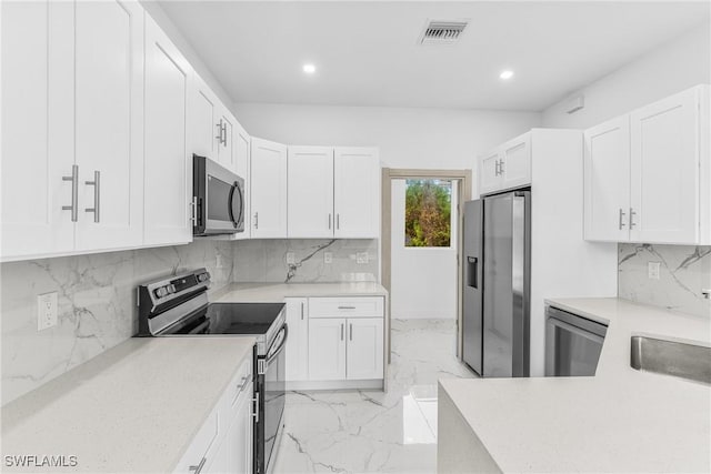 kitchen featuring white cabinets, backsplash, and appliances with stainless steel finishes