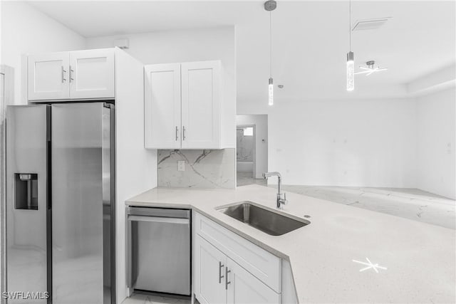 kitchen featuring pendant lighting, backsplash, sink, appliances with stainless steel finishes, and white cabinetry