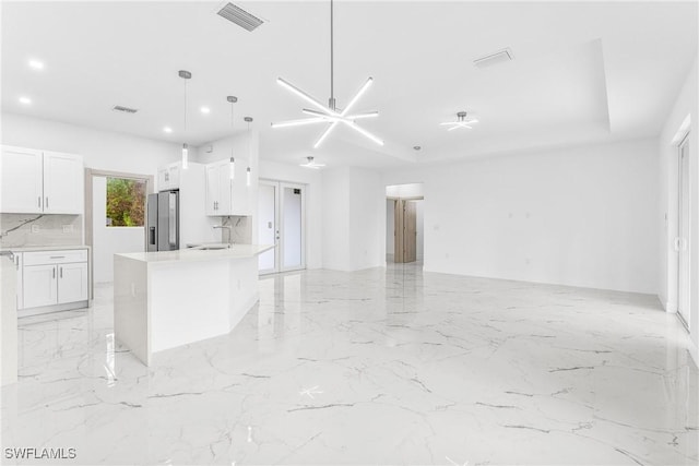 kitchen featuring a kitchen island, stainless steel fridge with ice dispenser, decorative light fixtures, decorative backsplash, and white cabinets