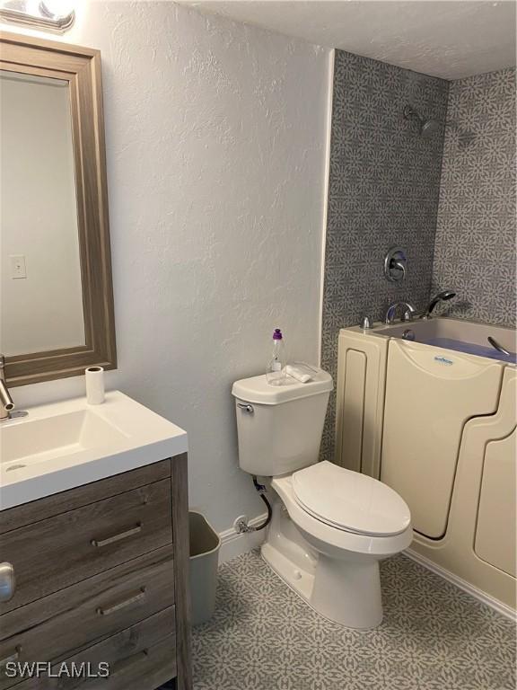 bathroom with vanity, tile patterned flooring, a shower, and toilet