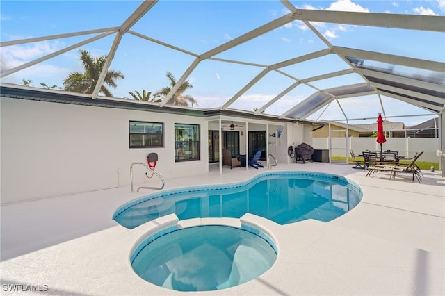 view of swimming pool featuring an in ground hot tub, glass enclosure, ceiling fan, and a patio area