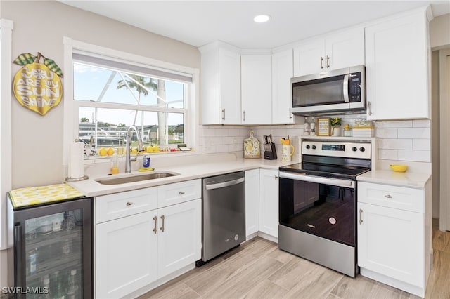 kitchen with white cabinets, sink, beverage cooler, and stainless steel appliances