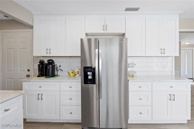 kitchen featuring white cabinets, stainless steel fridge with ice dispenser, and tasteful backsplash