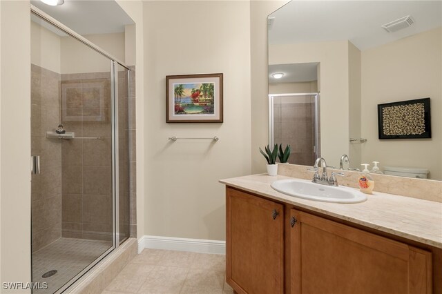 bathroom with tile patterned floors, a shower with door, vanity, and toilet