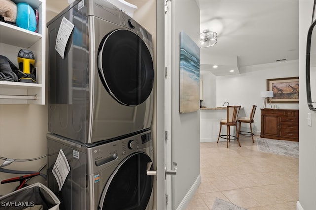 washroom with light tile patterned floors and stacked washer / drying machine