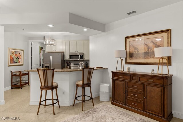 kitchen featuring sink, hanging light fixtures, stainless steel appliances, a kitchen breakfast bar, and dark stone counters