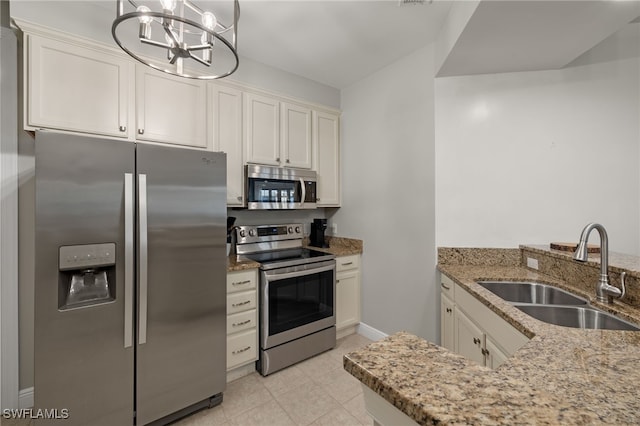 kitchen with sink, stainless steel appliances, light stone counters, decorative light fixtures, and white cabinets