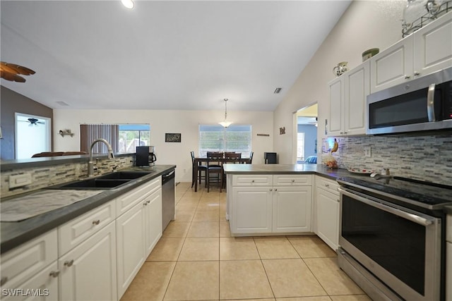 kitchen with decorative backsplash, appliances with stainless steel finishes, sink, white cabinets, and lofted ceiling