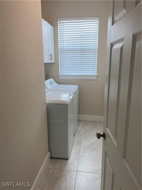 washroom with washer and dryer, cabinets, and light tile patterned flooring