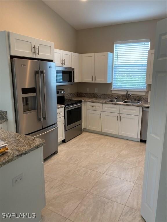 kitchen featuring white cabinets, dark stone countertops, sink, and stainless steel appliances