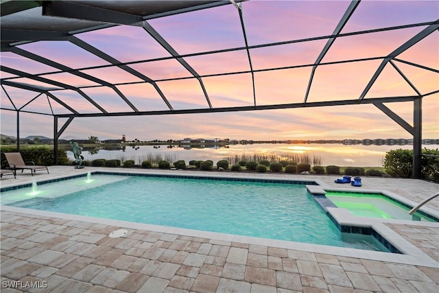 pool at dusk with a lanai, a patio area, a water view, and an in ground hot tub