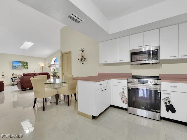 kitchen featuring light tile patterned floors, white cabinetry, kitchen peninsula, and appliances with stainless steel finishes