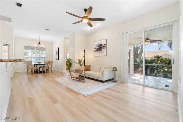 living room featuring light hardwood / wood-style floors and ceiling fan with notable chandelier