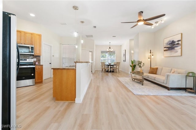 kitchen featuring ceiling fan, hanging light fixtures, light hardwood / wood-style flooring, decorative backsplash, and appliances with stainless steel finishes