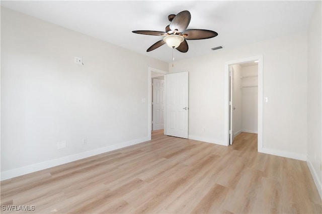 unfurnished bedroom with ceiling fan, light wood-type flooring, a spacious closet, and a closet