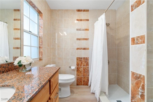 bathroom featuring vanity, a shower with curtain, hardwood / wood-style flooring, toilet, and tile walls