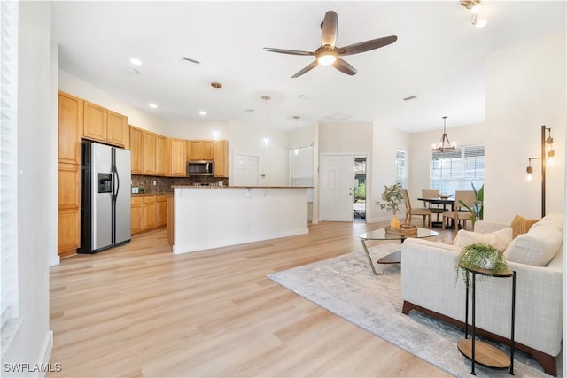 living room with light wood-type flooring and ceiling fan with notable chandelier