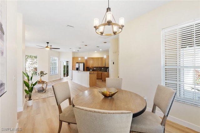 dining space featuring ceiling fan with notable chandelier and light hardwood / wood-style flooring