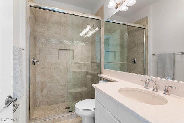 bathroom featuring vanity, a shower with shower door, and toilet