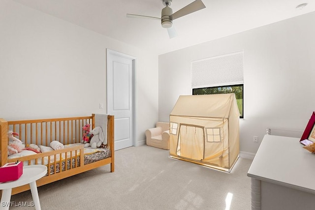 carpeted bedroom with ceiling fan and a crib