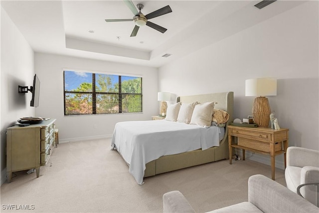 carpeted bedroom with a raised ceiling and ceiling fan