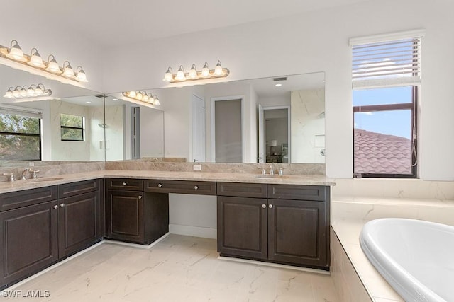 bathroom featuring vanity, a relaxing tiled tub, and a healthy amount of sunlight