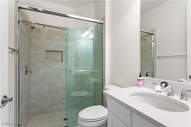 bathroom featuring a shower with door, vanity, and toilet