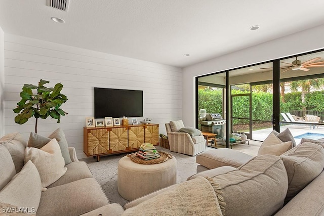 living room featuring ceiling fan and wood walls