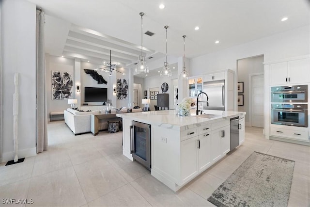 kitchen featuring stainless steel appliances, a large island with sink, white cabinets, wine cooler, and hanging light fixtures