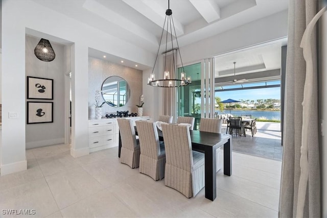 dining area featuring light tile patterned floors, a water view, a raised ceiling, and a healthy amount of sunlight