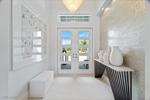 entryway featuring french doors, light tile patterned floors, and an inviting chandelier