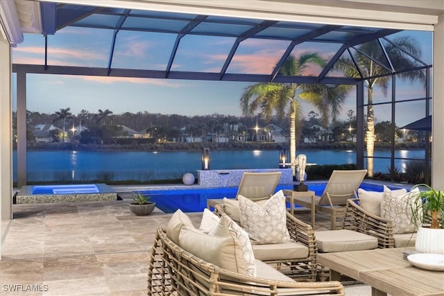 patio terrace at dusk with a lanai, a water view, and an outdoor hangout area