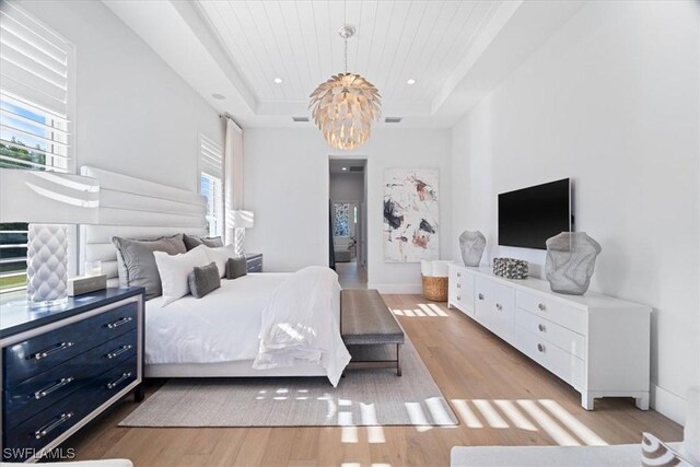 bedroom with light hardwood / wood-style floors, a raised ceiling, wood ceiling, and an inviting chandelier