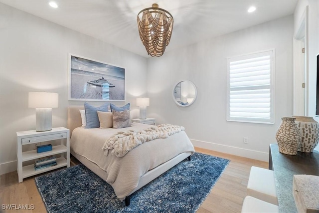 bedroom with light hardwood / wood-style floors and a notable chandelier