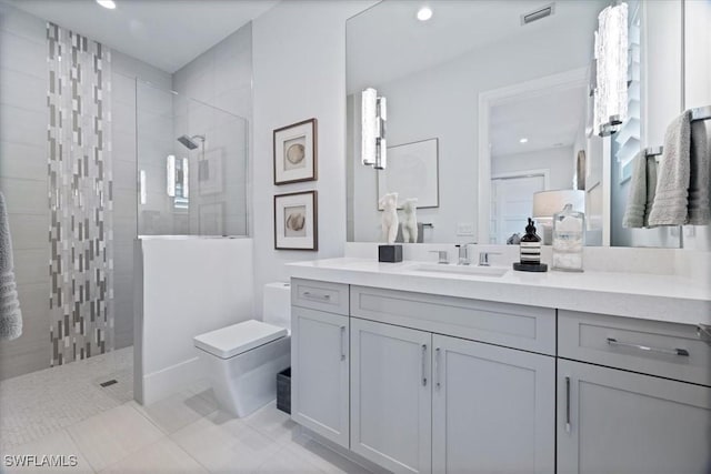 bathroom with a tile shower, tile patterned flooring, vanity, and toilet